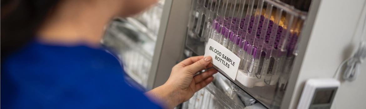 Een vrouwelijke laborante brengt een gedrukt etiket aan op flessen met bloedmonsters