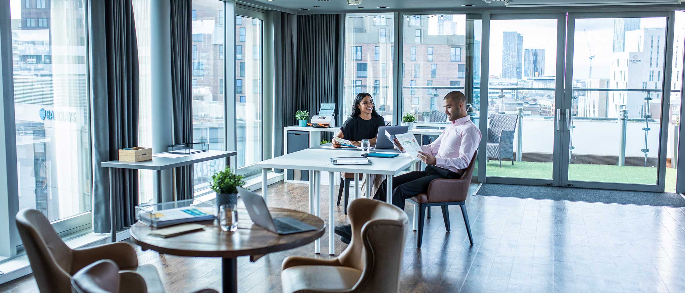 Een man en een vrouw zitten aan een bureau op hun werkplek, bureau, stoelen, scanner, gebouwen