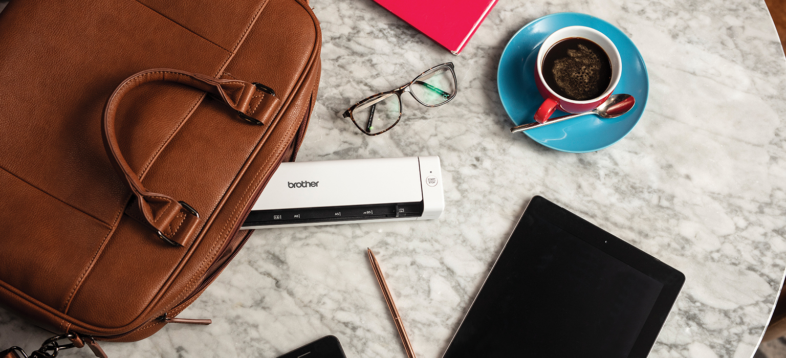 top down view of desk with; brother mobile printer, coffee and a tablet