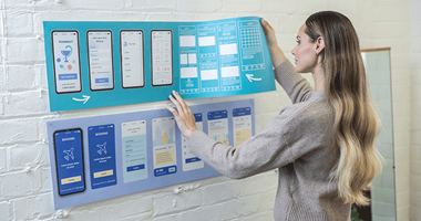 Female holding large format printed documents putting up on wall