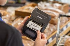 Impression d'étiquettes de promotion à partir de l'imprimante mobile robuste Brother RJ-3200 devant un étale de pain.