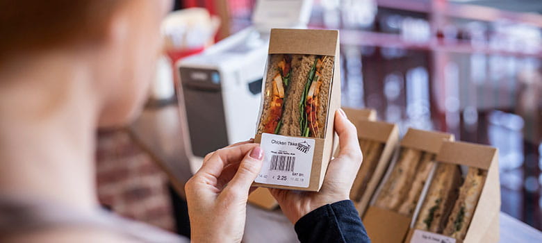 Application d'une étiquette alimentaire sur un sandwich dans une charcuterie