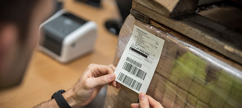 Verzendetiket wordt aangebracht op vergepakte bruine dozen