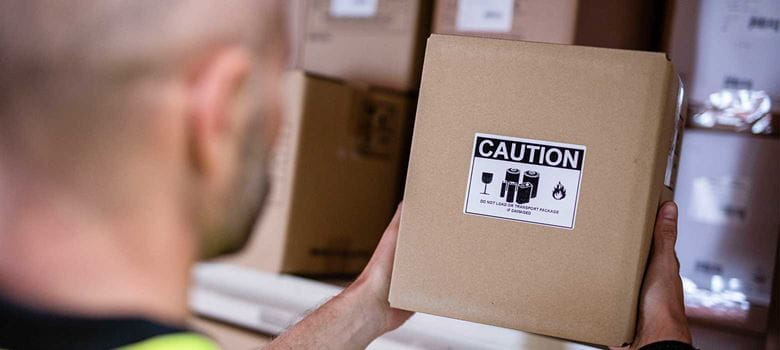 Man holding brown box with caution label in fulfilment centre