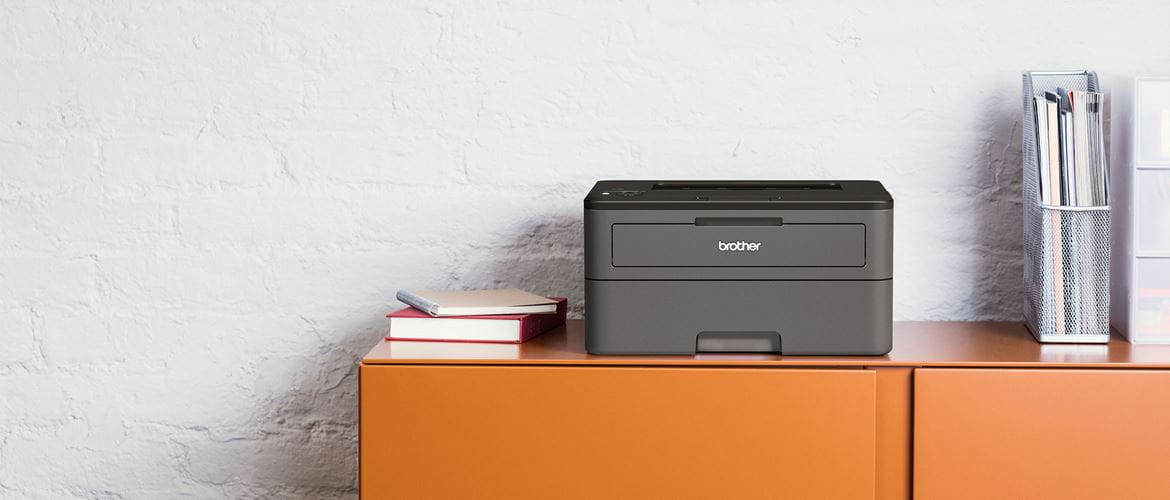 Tiskárna Brother HL-L2375DW na oranžové skříni, knihy, drátěný stojan na dokumenty, papír