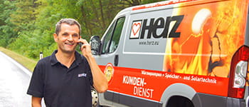 Serviser Herz govori po telefonu pokraj vozila Herz 