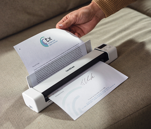 Ръчно подаване на лист хартия през скенер, който е поставен върху диван