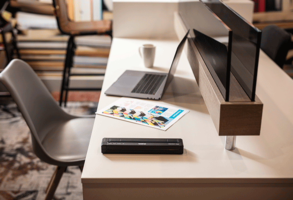 Мобилен принтер Brother серия PJ на бюро със сребърен лаптоп