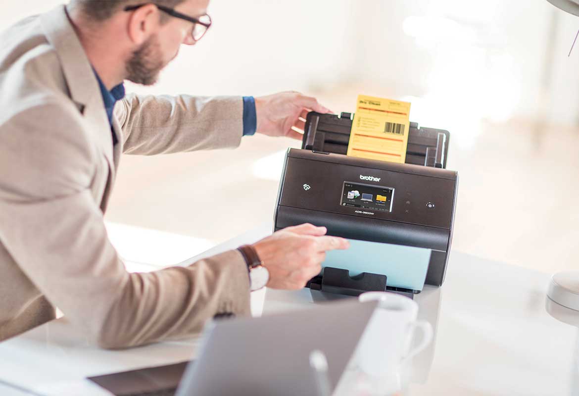 Muškarac s naočalima sijedi za stolom i skenira dokumenat s Barcode utility