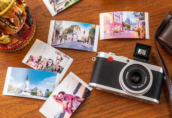 Egy asztalon elhelyezett fényképezőgép öt színes fényképpel