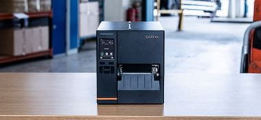 Imprimanta industriala neagră de etichete  stă pe masă în depozit