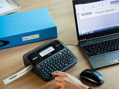 Tiskárna odolných štítků P-touch na kancelářském stole připojená k počítači