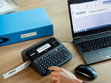 P-touch tartós címkenyomtató számítógéphez csatlakoztatva egy irodai íróasztalon