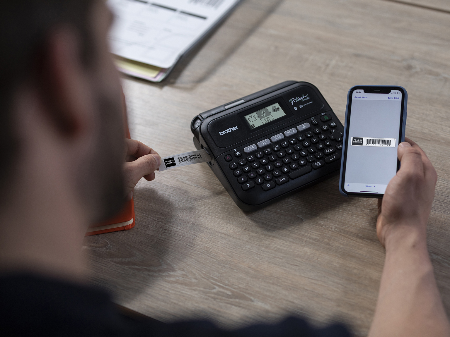 Omul editează și imprimă etichete folosind aplicația iPrint&Label, partajată din software-ul Brother P-touch Editor 6.0 de proiectare a etichetelor