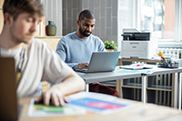 Bărbat care examinează pagini full color stând lângă Brother MFC-L3740CDW