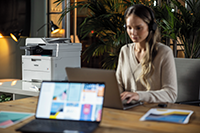 Žena pracujúca na počítači, tlačiareň Brother v pozadí