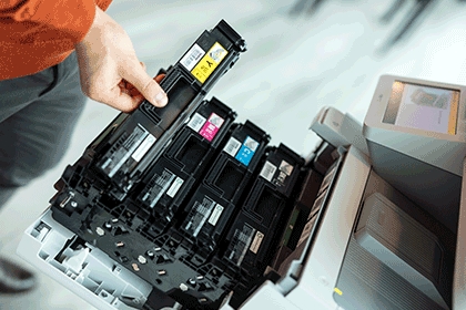 Ruka vyťahujúca toner z tlačiarne, držiaca žltý toner
