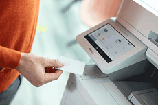 O persoană ține cardul NFC pe o imprimantă multifuncțională