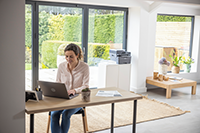 Woman using laptop to operate Brother printer