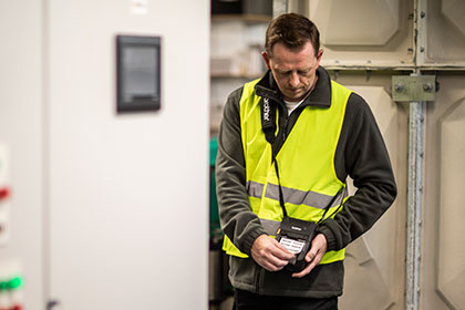 Údržbář v reflexní vestě v kotelně tiskne dokument z tiskárny Brother RJ-3200 na ramenním popruhu