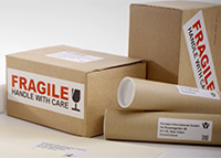 Adresă și etichete fragile lipite de ambalajele din carton maro