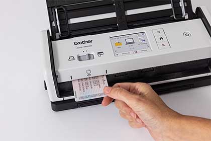 Osoba wkłada kartę plastikową do skanera Brother ADS-1800W