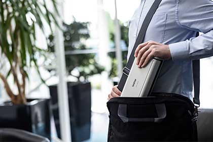 Osoba w niebieskiej koszuli wkłada skaner Brother ADS-1800W do czarnej torby