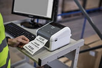 Mężczyzna drukuje etykietę w magazynie przy użyciu komputera i drukarki z serii TD-4D
