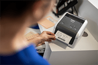 Медицинска сестра отпечатва етикет на пациент с помощта на настолен етикетен принтер Brother TD-4410D