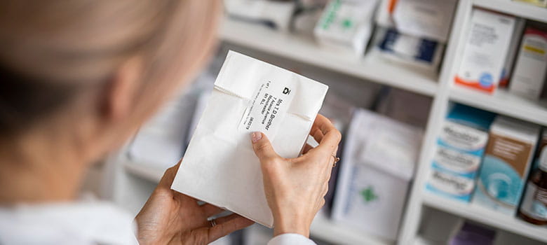 Фармацефт поставя етикет на пакет с лекарства в аптека