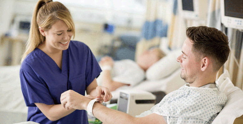 Asistentă punând brățara pe încheietura mâinii pacientului de sex masculin