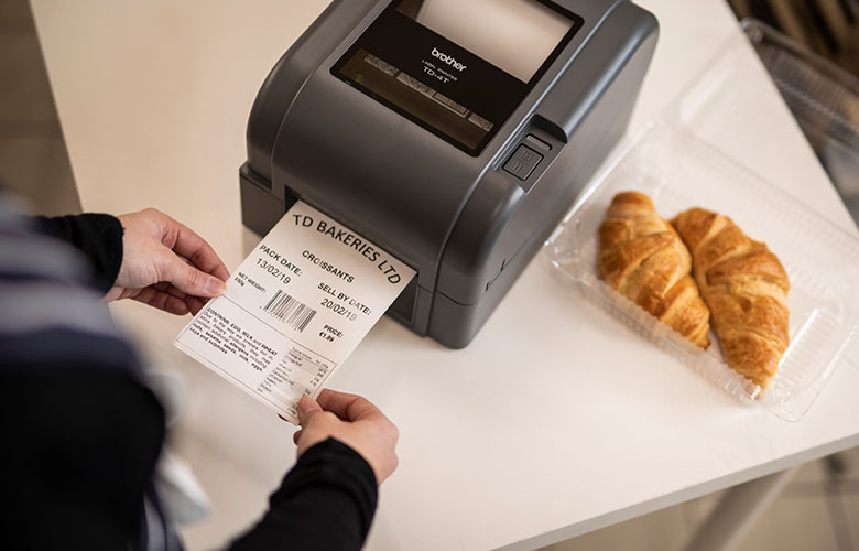 Stolní tiskárna Brother TD s termotransferovým tiskem generuje štítek na balení croissantů