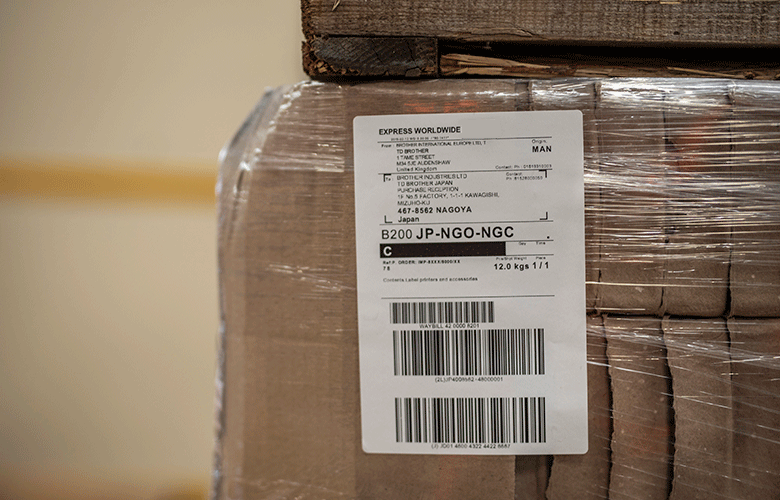Primplan al unei etichete logistice albe lipita pe o cutie maro impachetata
