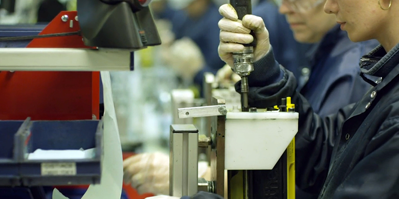 O femeie și un bărbat operează un echipament într-o fabrică