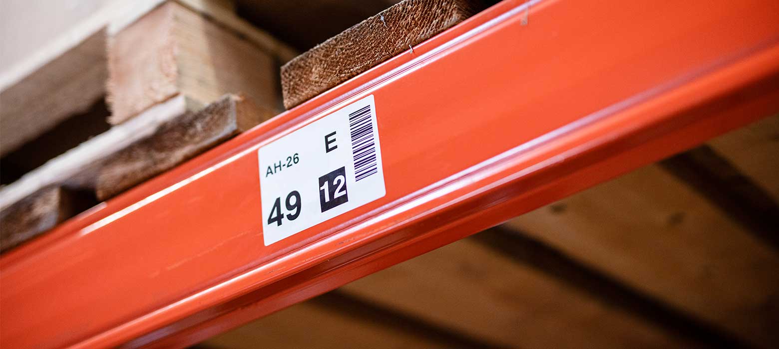 Oranžové regály s čárovým kódem a čísly na štítku ve skladu