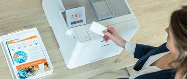 Frau mit Chipkarte in der Hand vor einem Drucker.