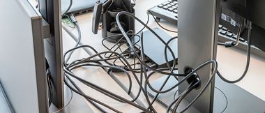 Das Bild zeigt einen Schreibtisch mit vielen Kabeln.