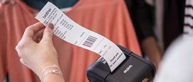 Frau in Bekleidungsgeschäft zieht Kassenbeleg aus Etikettendrucker