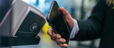 Person bezahlt per Smartphone an NFC-Terminal