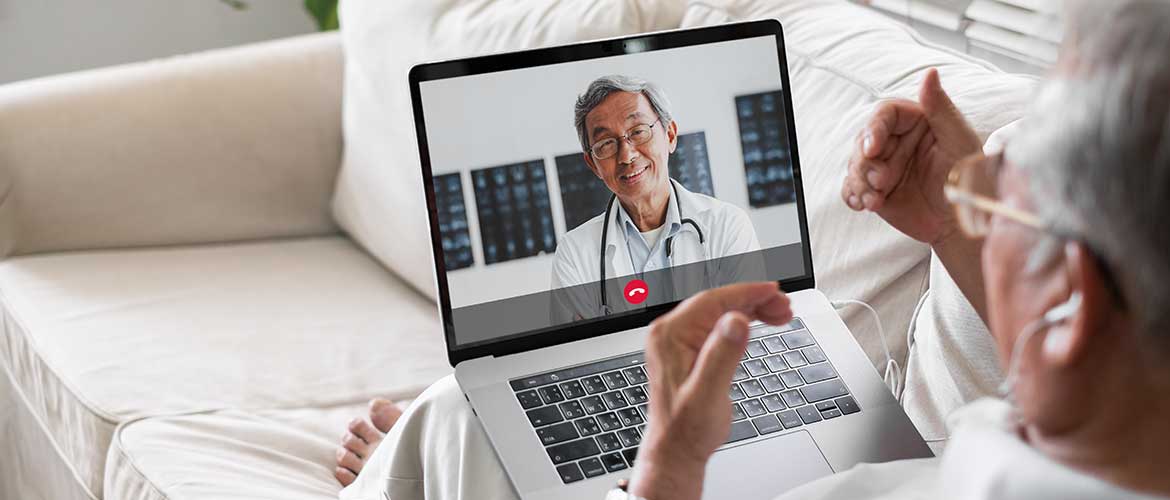 Mann mit Laptop auf dem Sofa in einem Videokonferenz mit Seinem Doktor