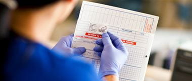 Ärztin beklebt Patientenakte mit einem personalisierten Label