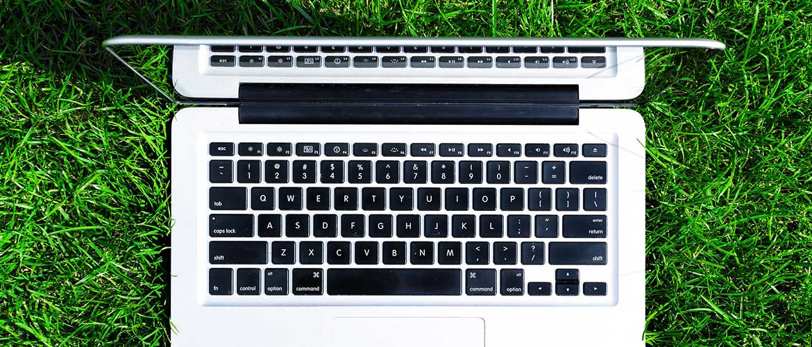Aufgeklappter Laptop von Oben, der auf Einer Grünen Wiese heht.