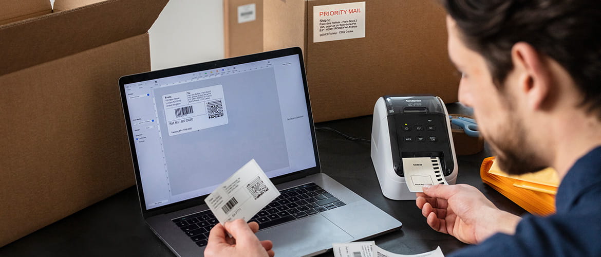 Mann drucken versandetiketten für pakete am laptop über einen etikettendrucker.