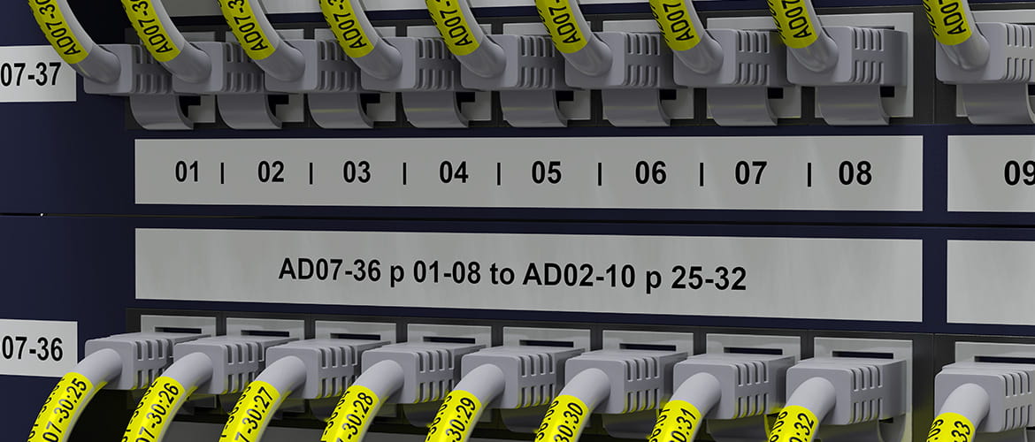 Verteilerblock mit diversen Netzwerkkabeln in Ports. Farbige Etiketten zur Kennzeichnung. 