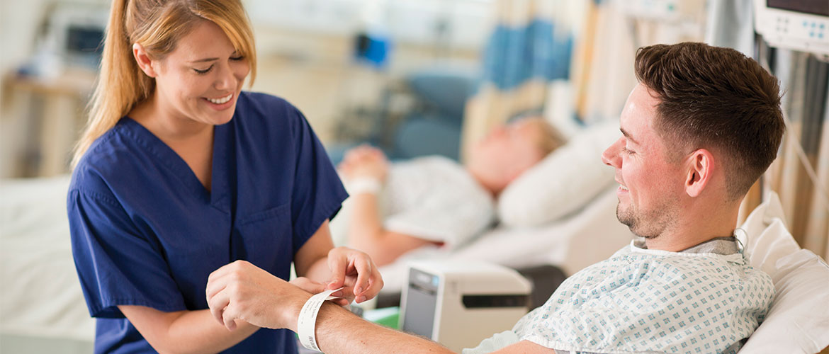 Krankenpflegerin legt Patient Patientenarmband aus Etikettendrucker um Handgelenk