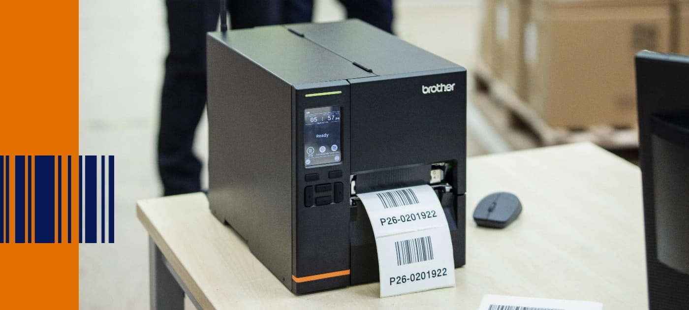 Ein industrieller Etikettendrucker der TJ-Serie von brother mit Barcode-Etikettenausgabe auf einem Schreibtisch in einer Lagerumgebung