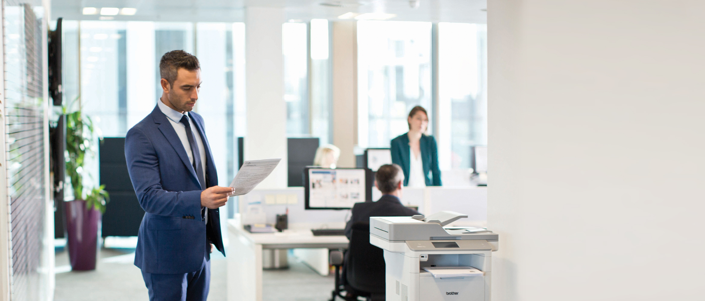 Büromitarbeitlicher Schaut auf Ausdruck, Vor Brother Drucker Stehend, Büro im Hintergrund