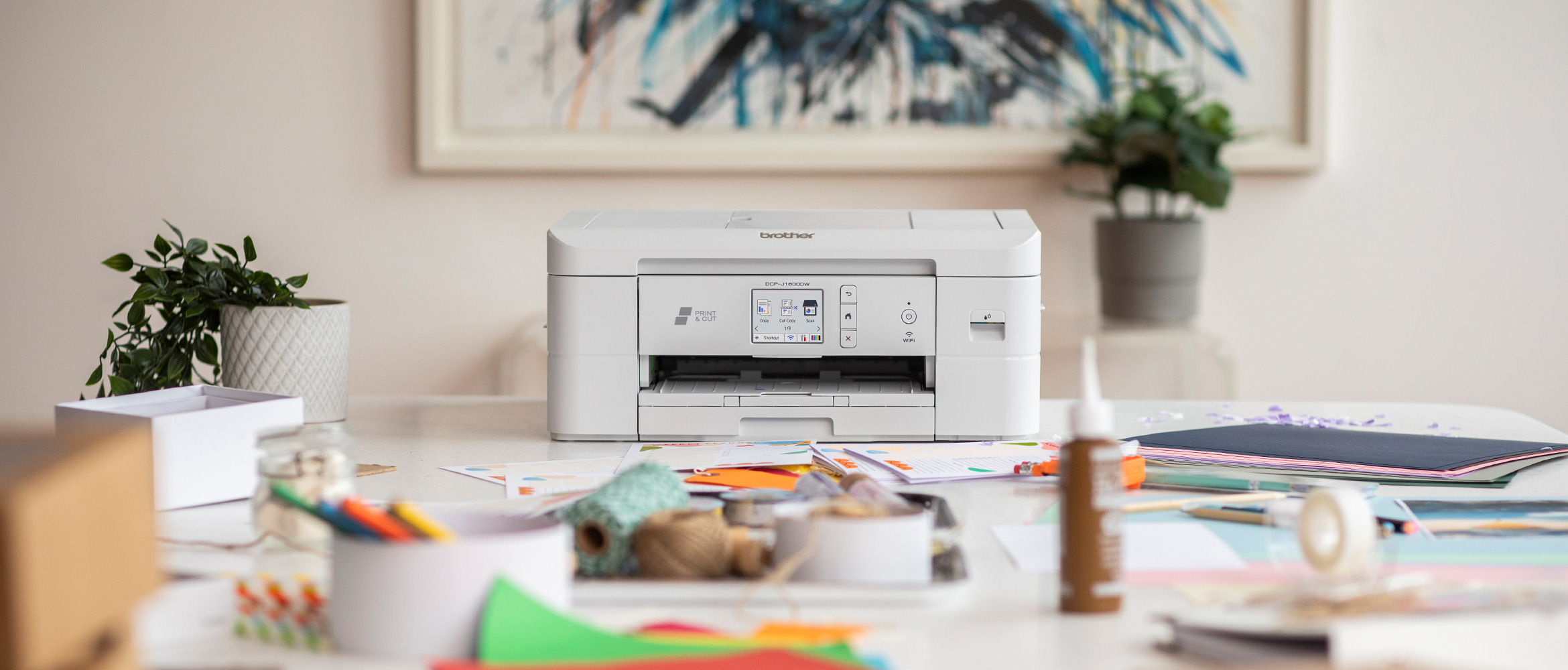 DCP-J1800DW Print & Cut, auf Tisch stehend mit Kreativmaterialien