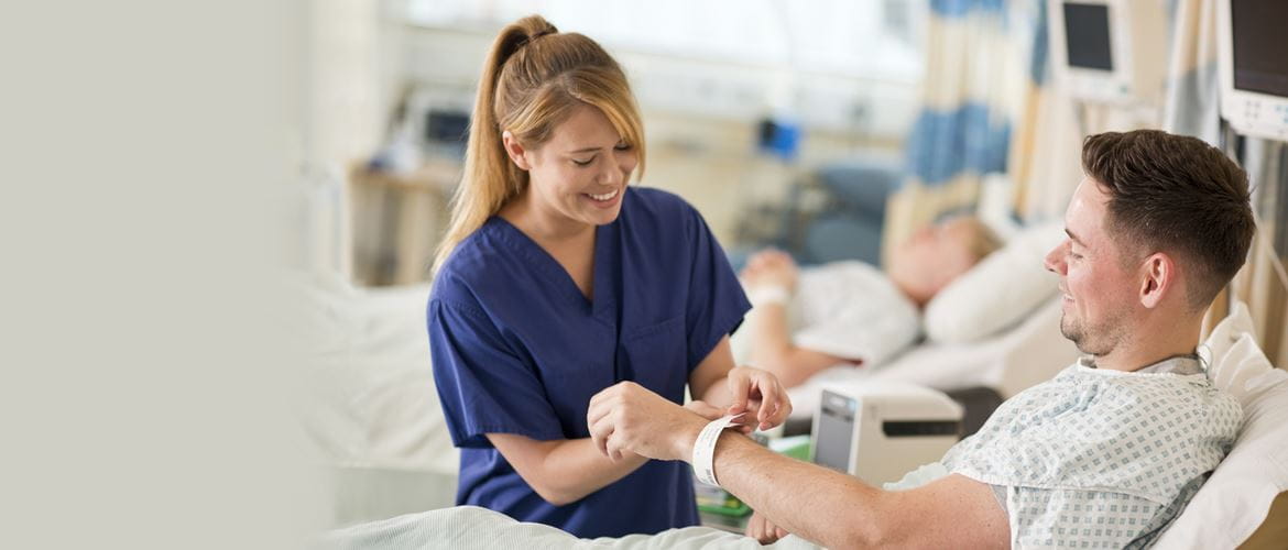Krankenschwester, lächelnd, legt Patient Armband an