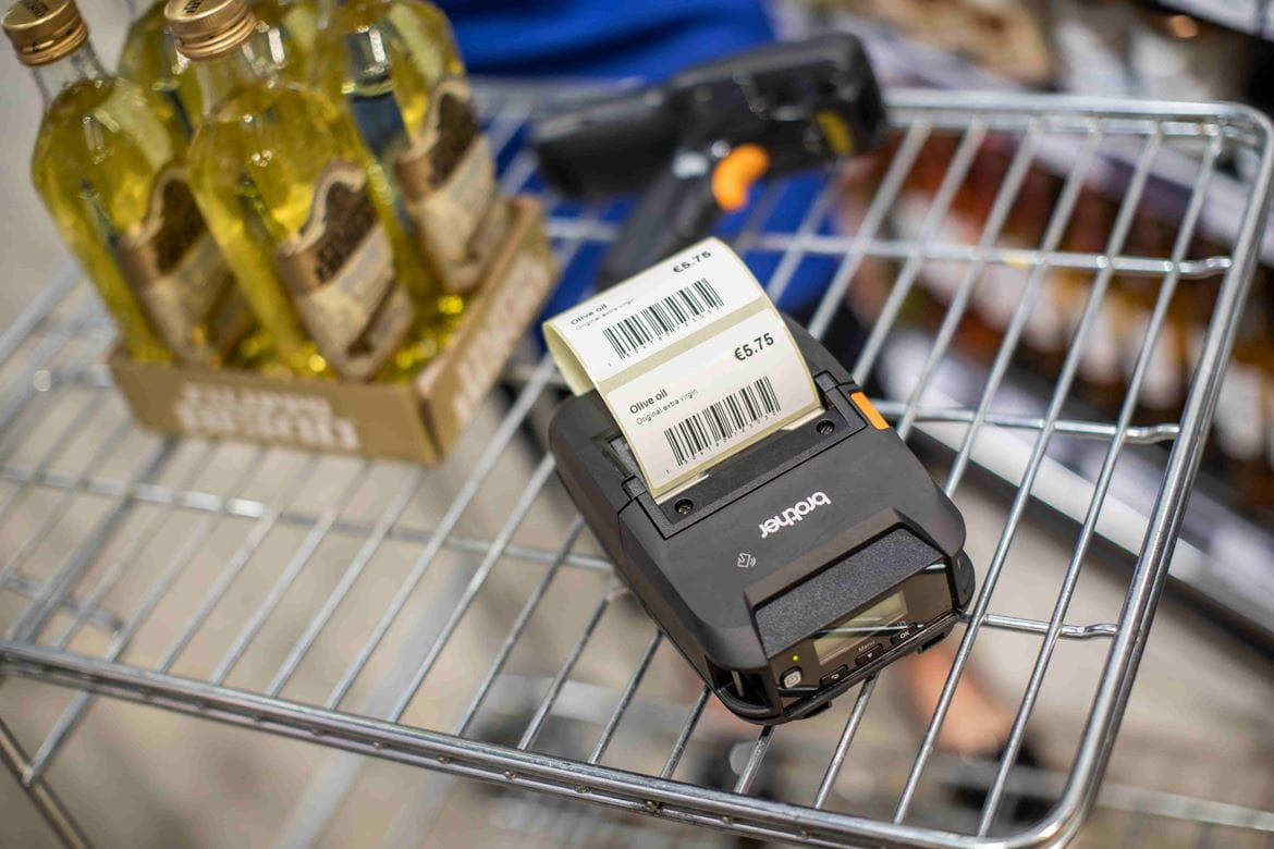 Ein Einkaufswagen, der Olivenöl und einen Etikettendrucker beinhaltet.